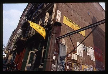 Street façade with yellow awnings, signs and graffiti