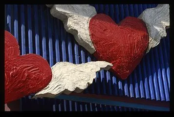 Sculptures of red hearts with white wings on a blue background